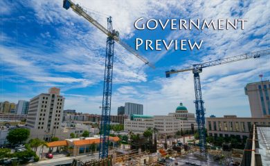 Cranes next to buildings on a sunny day text reads Government Preview.